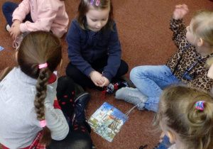 Grupka dzieci siedząca w kółeczku. W środku ułożone przez dzieci puzzle.